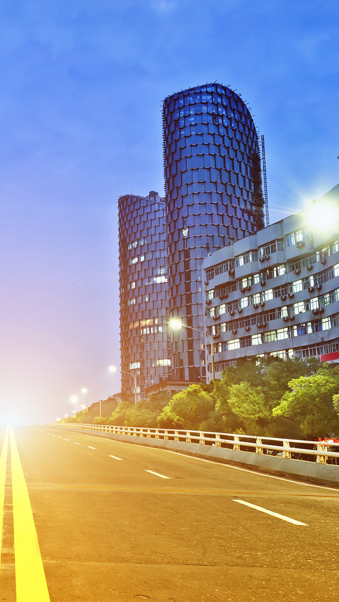 Gray Concrete Road Between Green Trees and High Rise Buildings During Daytime. Wallpaper in 1080x1920 Resolution