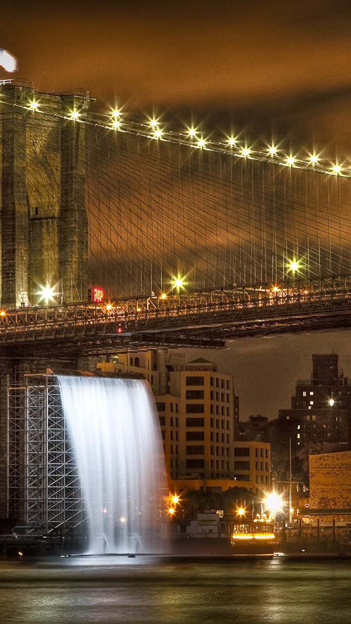 Puente Iluminado Cerca de Los Edificios de la Ciudad Durante la Noche.. Wallpaper in 720x1280 Resolution