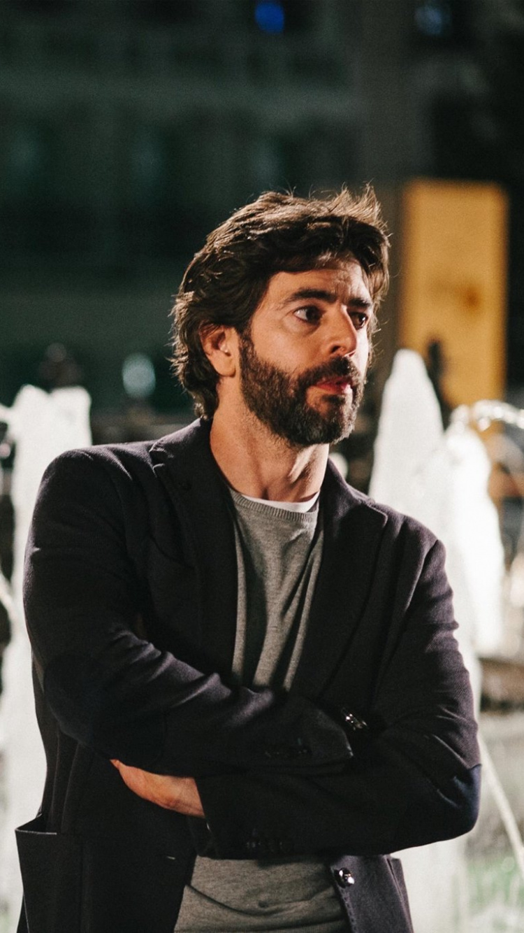 Man in Black Jacket Standing Near Water Fountain During Daytime. Wallpaper in 750x1334 Resolution