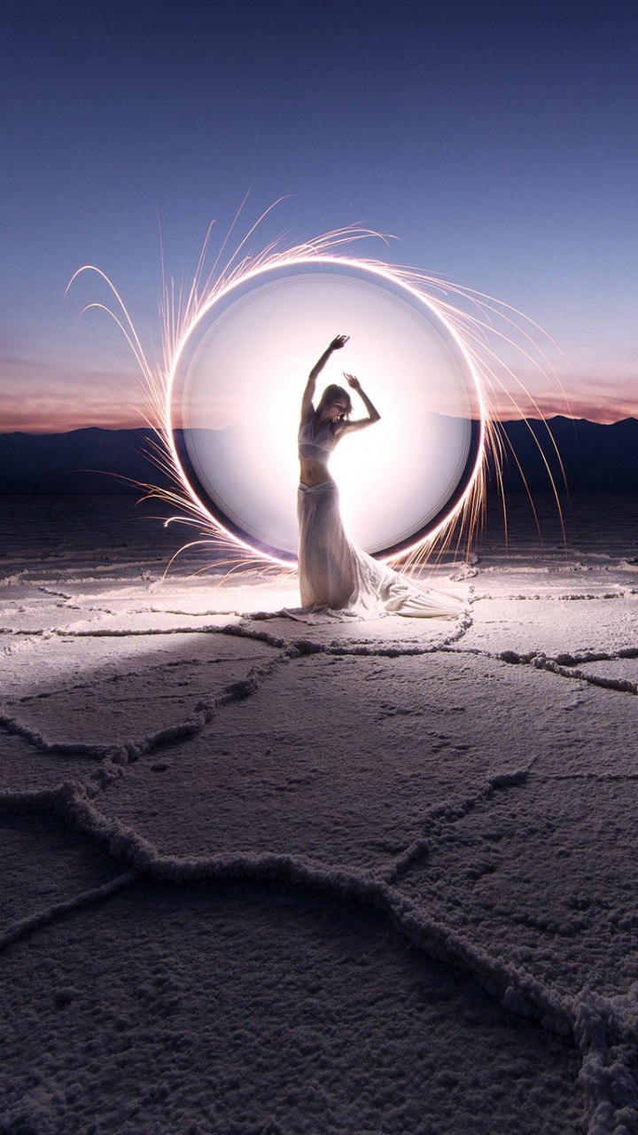 Person in White Shirt Sitting on Sand During Night Time. Wallpaper in 720x1280 Resolution