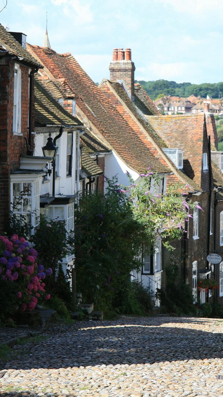 Leute, Die Tagsüber Auf Der Straße Zwischen Den Häusern Gehen. Wallpaper in 720x1280 Resolution