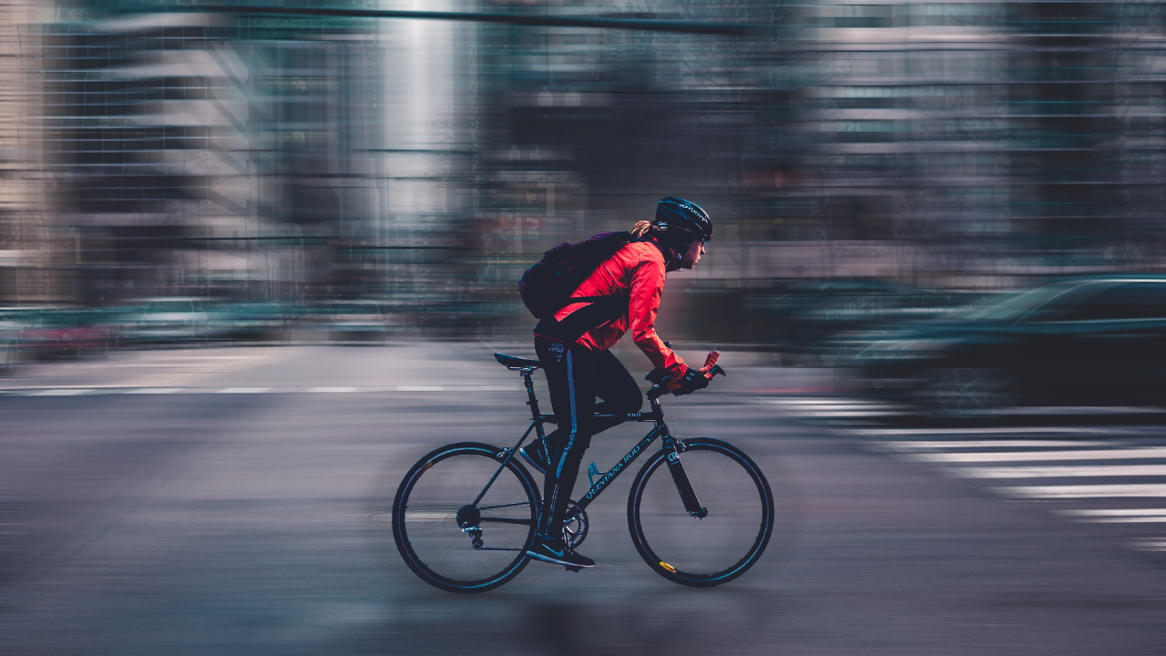 Man in Red Jacket Riding Bicycle Sur Route Pendant la Journée. Wallpaper in 1280x720 Resolution