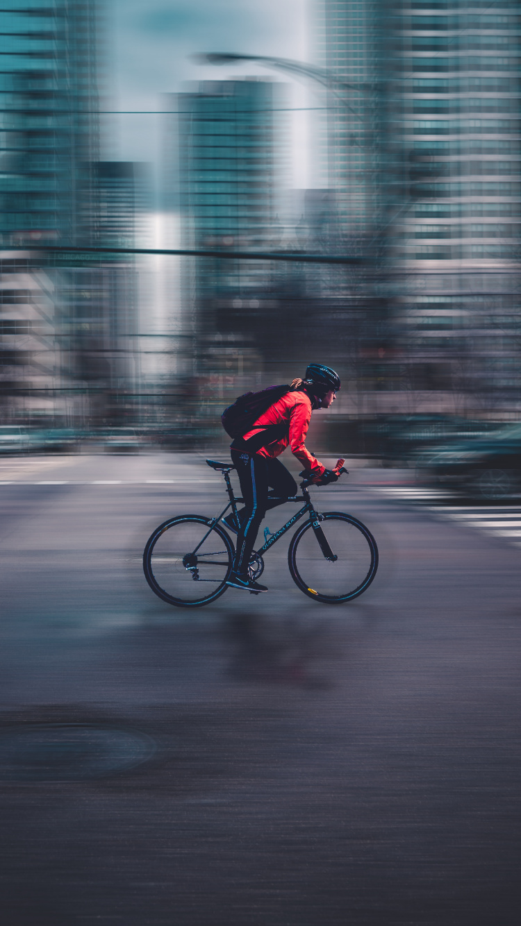 Hombre de Chaqueta Roja Montando Bicicleta en la Carretera Durante el Día. Wallpaper in 750x1334 Resolution