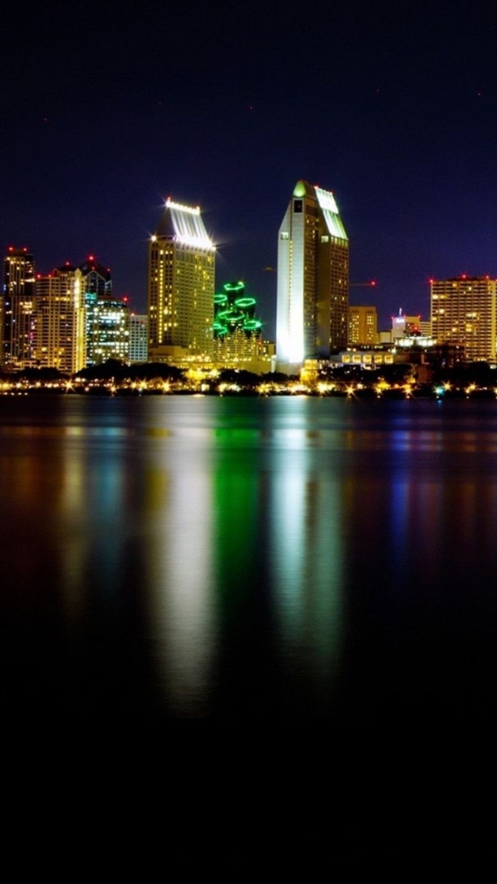 Skyline Der Stadt Über Gewässer Während Der Nacht. Wallpaper in 720x1280 Resolution