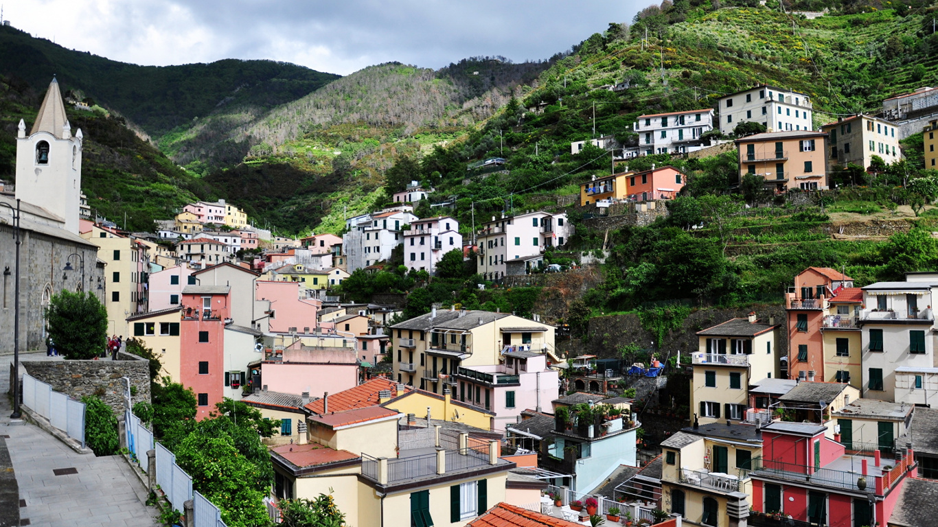 White and Brown Concrete Houses Near Green Mountain During Daytime. Wallpaper in 1366x768 Resolution