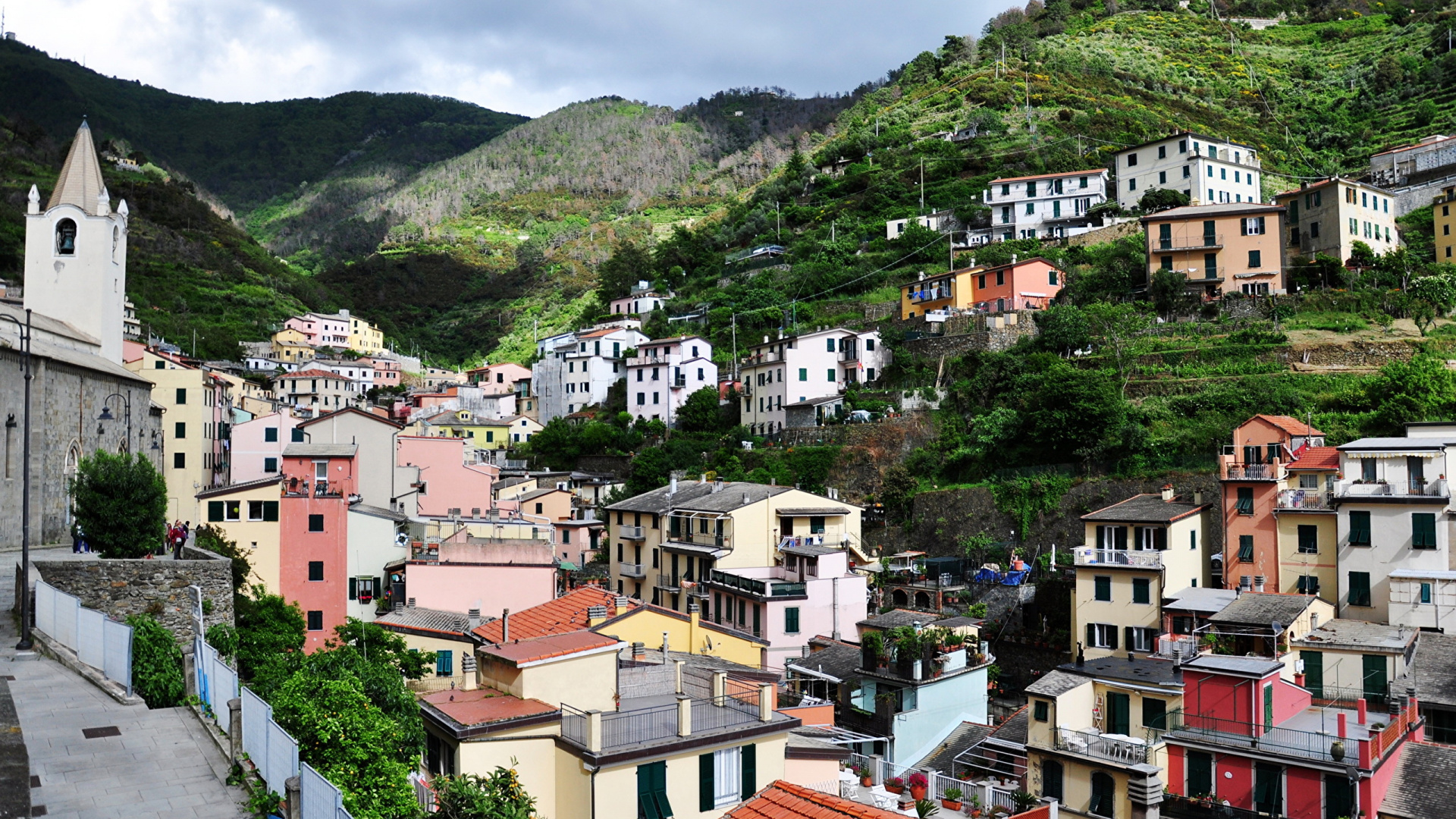 White and Brown Concrete Houses Near Green Mountain During Daytime. Wallpaper in 1920x1080 Resolution