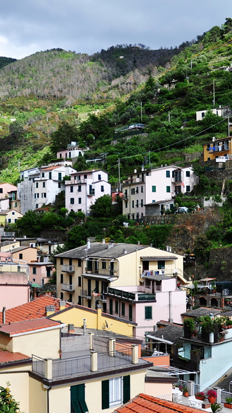 White and Brown Concrete Houses Near Green Mountain During Daytime. Wallpaper in 750x1334 Resolution