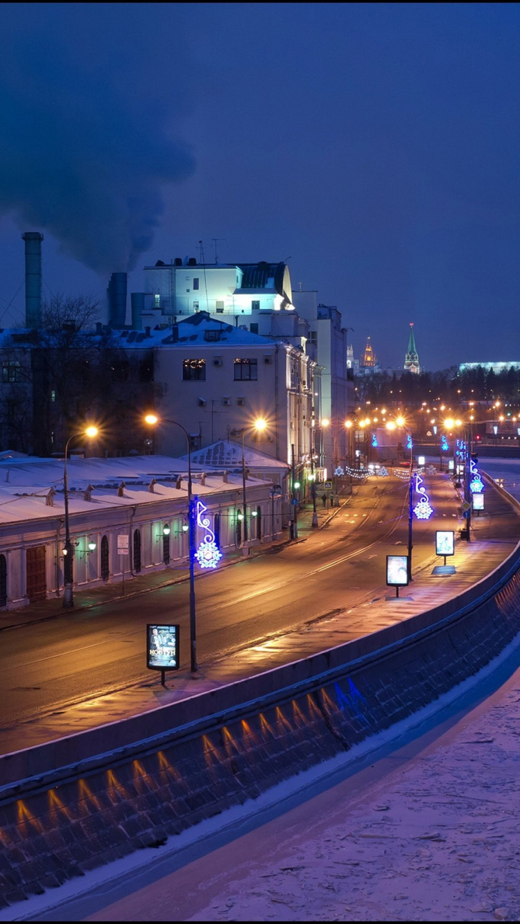 Weißes Und Blaues Betongebäude in Der Nähe Eines Gewässers Während Der Nacht. Wallpaper in 750x1334 Resolution