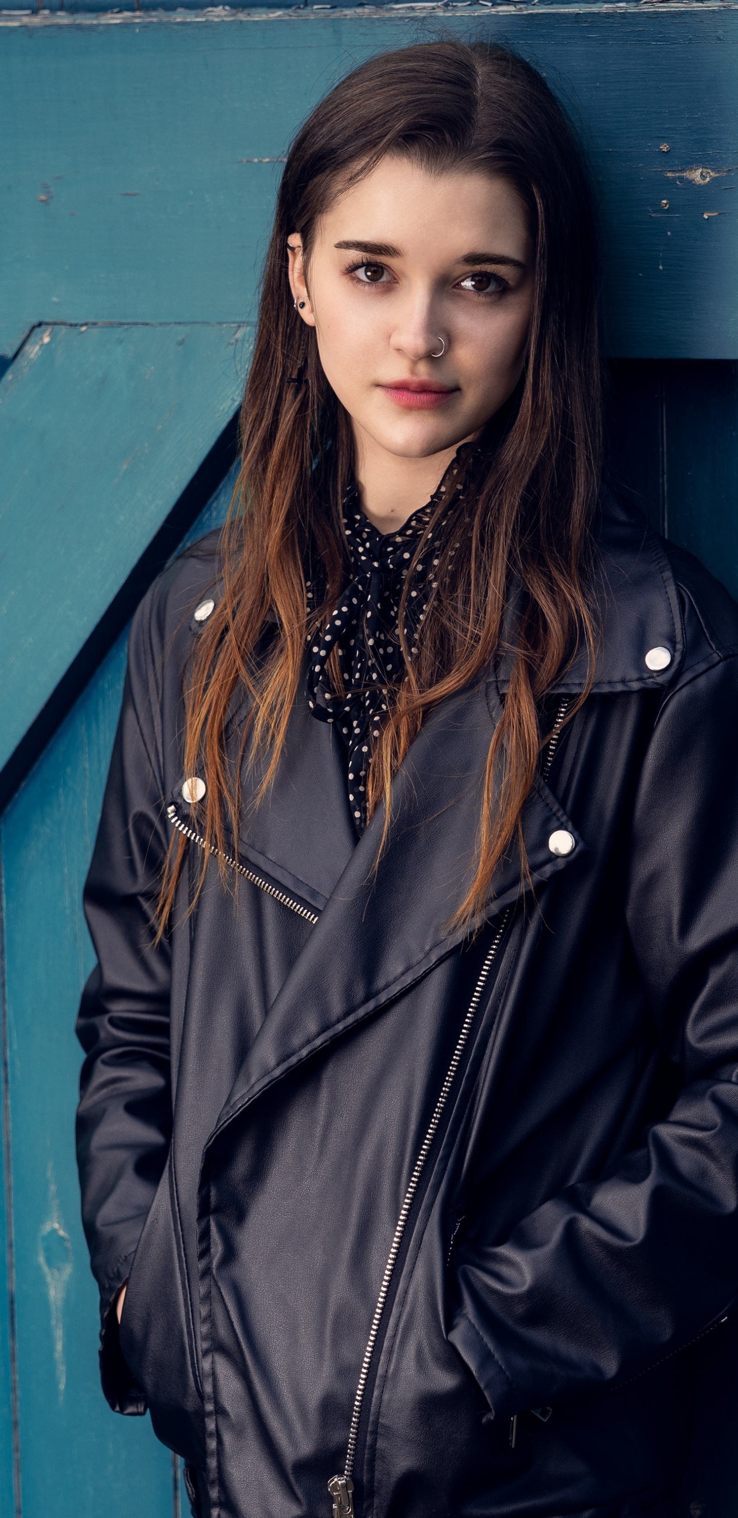 Frau im Schwarzen Mantel Steht Neben Blauer Holztür. Wallpaper in 1440x2960 Resolution