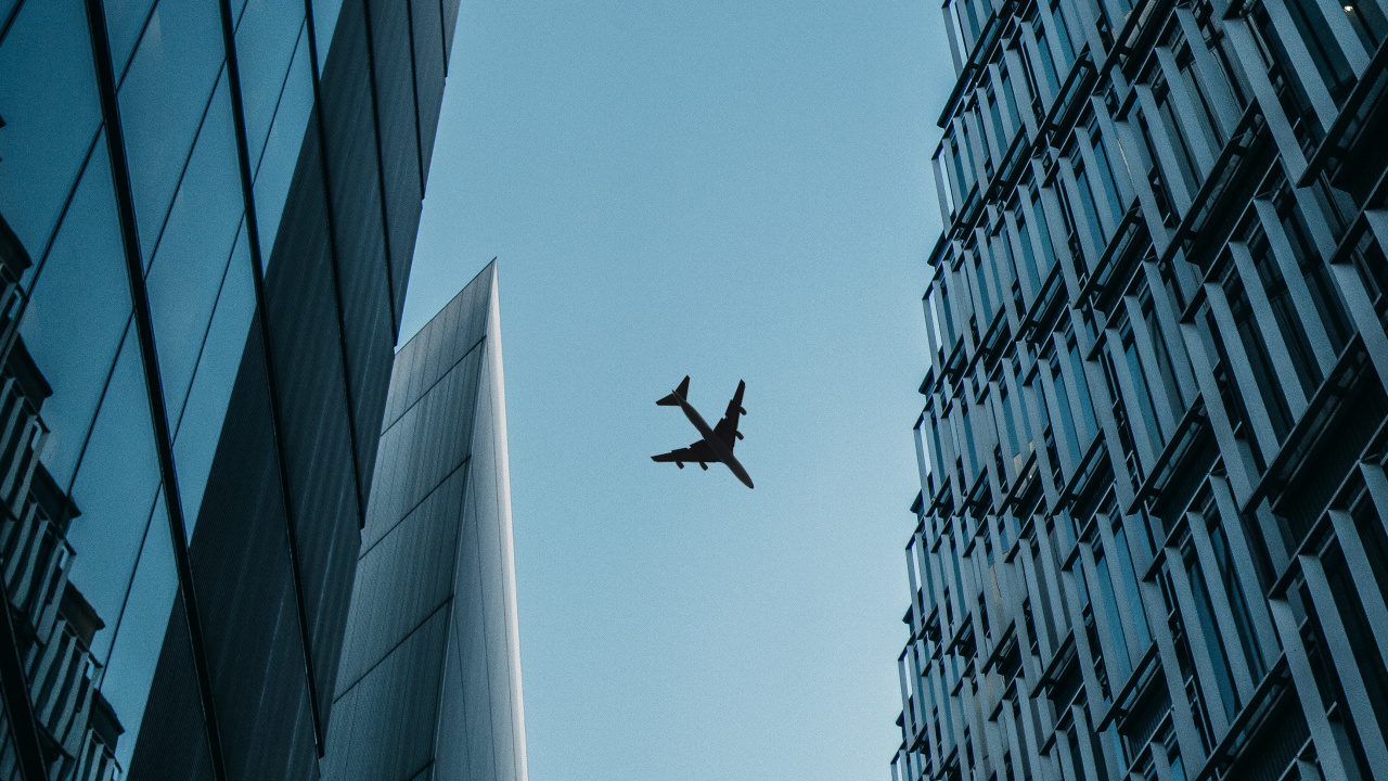 Airplane Flying Over The Building During Daytime. Wallpaper in 1280x720 Resolution