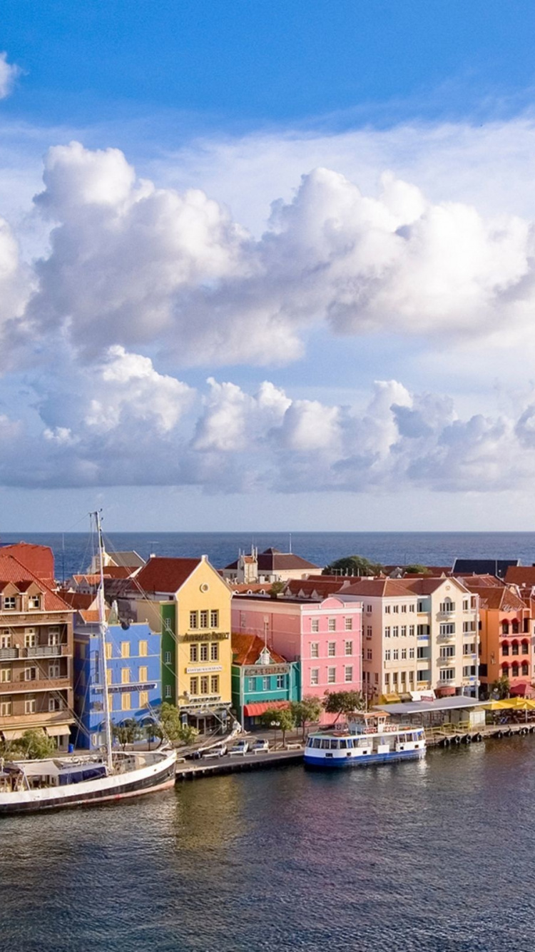White and Brown Concrete Buildings Near Body of Water Under Blue and White Cloudy Sky During. Wallpaper in 750x1334 Resolution
