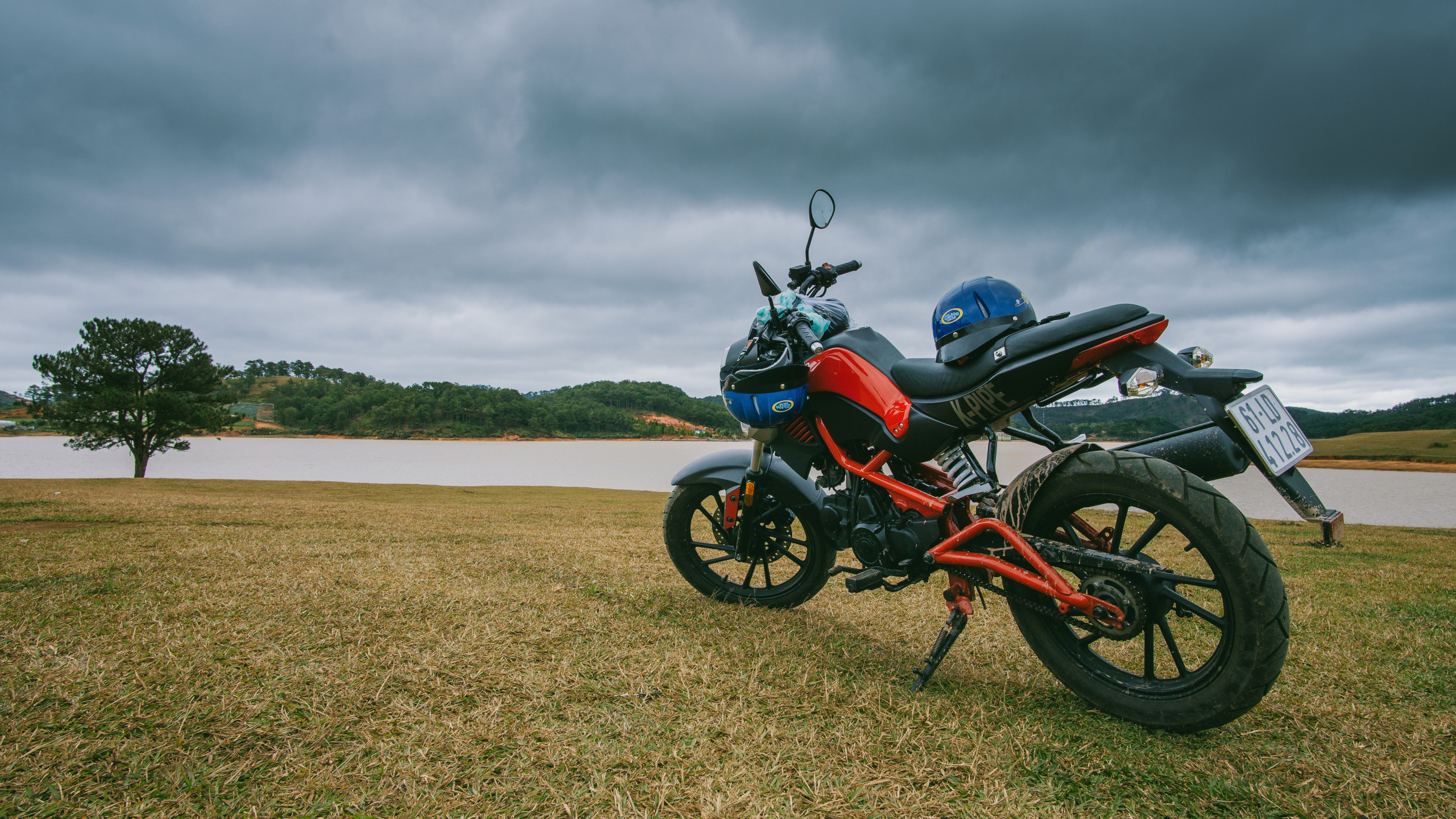 Red and Black Standard Motorcycle on Brown Field Under Gray Cloudy Sky. Wallpaper in 2560x1440 Resolution