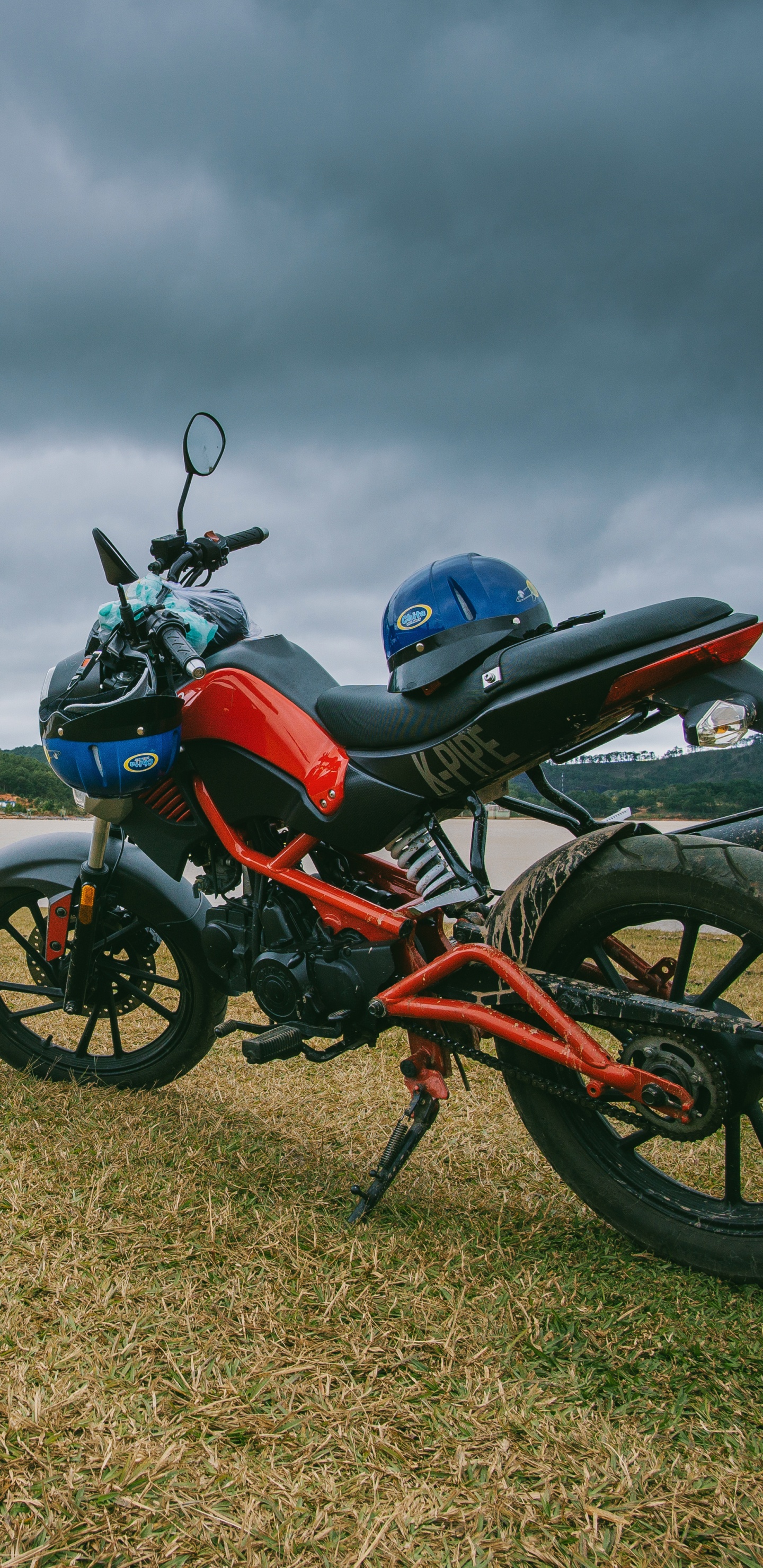 Moto Standard Rouge et Noir Sur Champ Brun Sous Ciel Nuageux Gris. Wallpaper in 1440x2960 Resolution