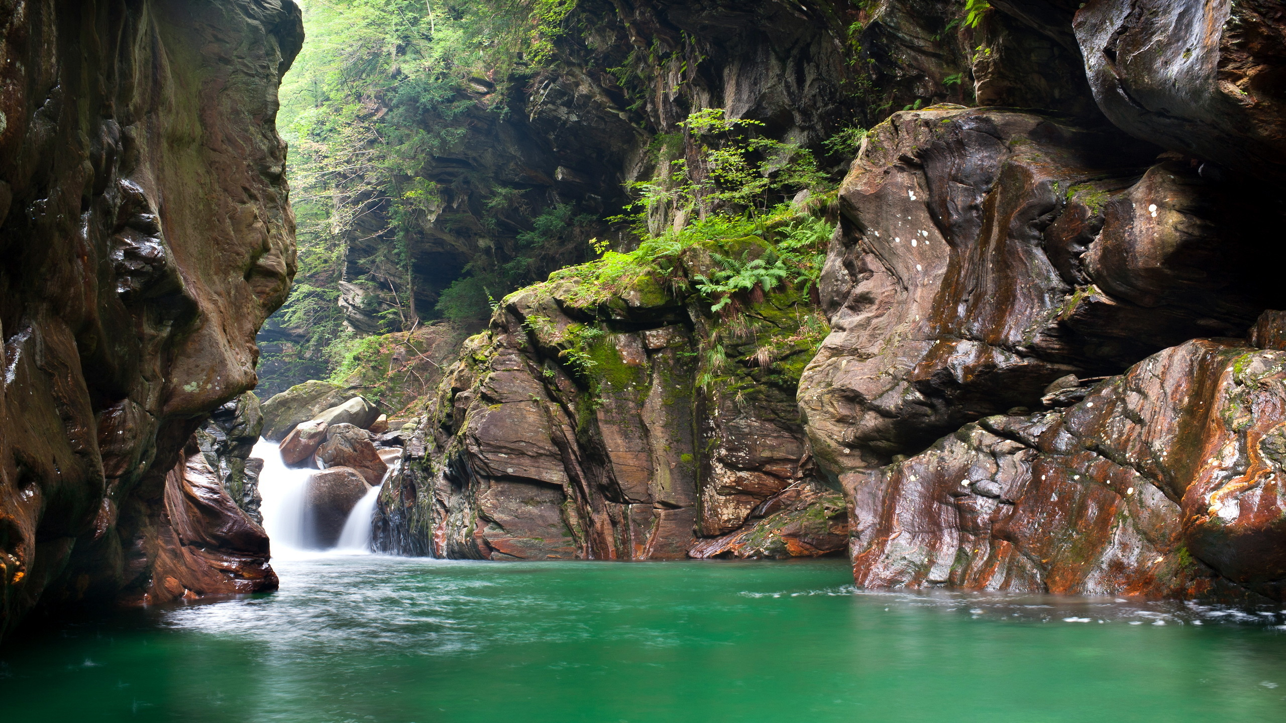 Water Falls Between Brown Rocky Mountain During Daytime. Wallpaper in 2560x1440 Resolution