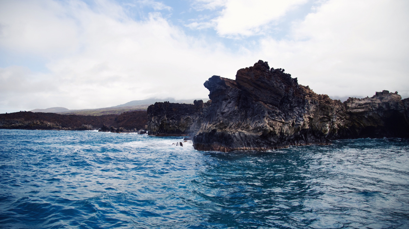 Brown and Green Rock Formation on Blue Sea Under White Clouds and Blue Sky During Daytime. Wallpaper in 1366x768 Resolution