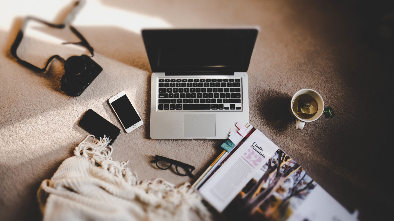 Macbook Pro à Côté D'un Smartphone Noir et de Lunettes de Soleil Noires. Wallpaper in 1366x768 Resolution