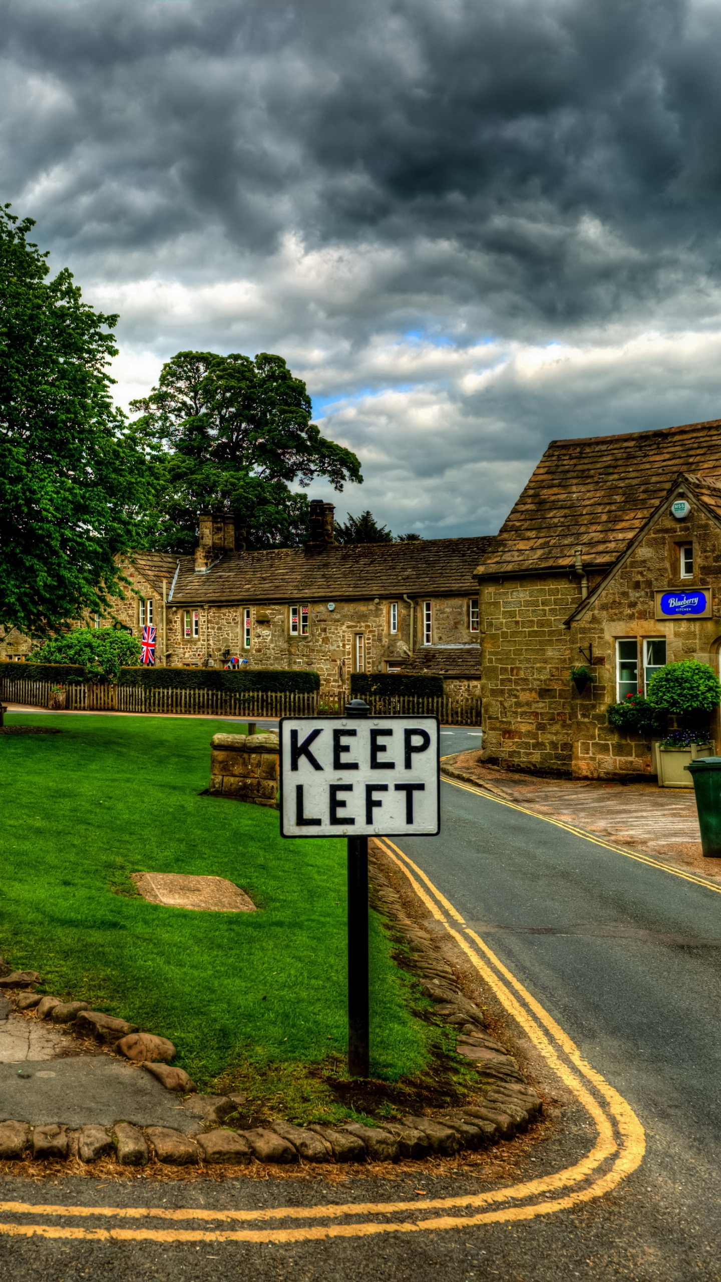 White and Black Road Sign Near Green Trees Under Cloudy Sky During Daytime. Wallpaper in 1440x2560 Resolution