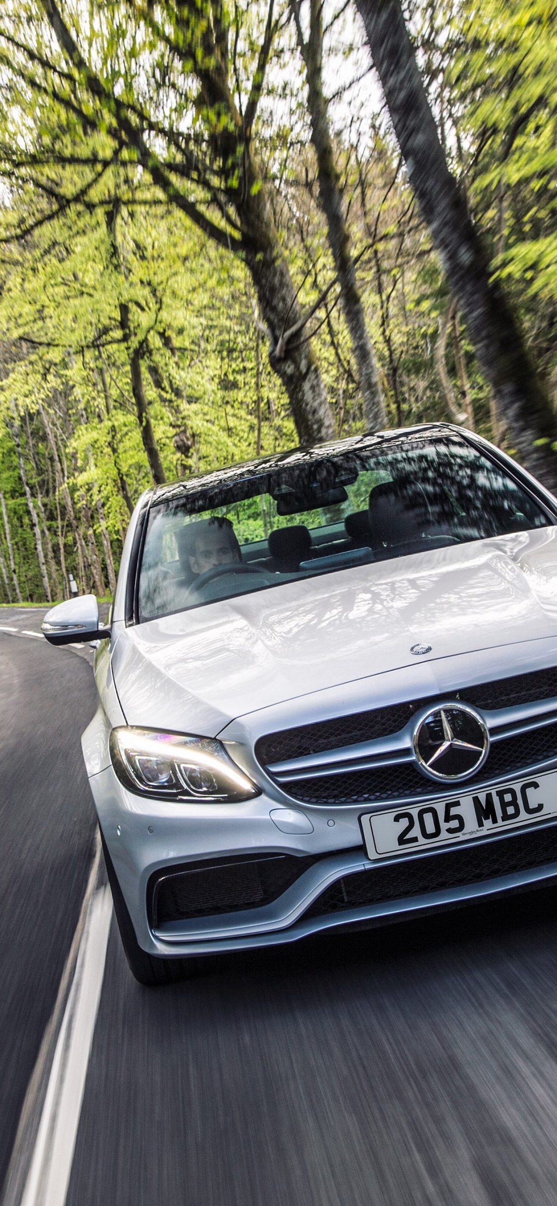 Silbernes Mercedes-Benz-Auto Auf Der Straße Zwischen Bäumen Tagsüber. Wallpaper in 1125x2436 Resolution