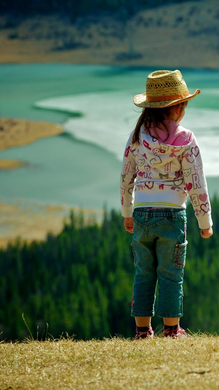 Girl in White Long Sleeve Shirt and Blue Denim Jeans Standing on Green Grass Field During. Wallpaper in 720x1280 Resolution