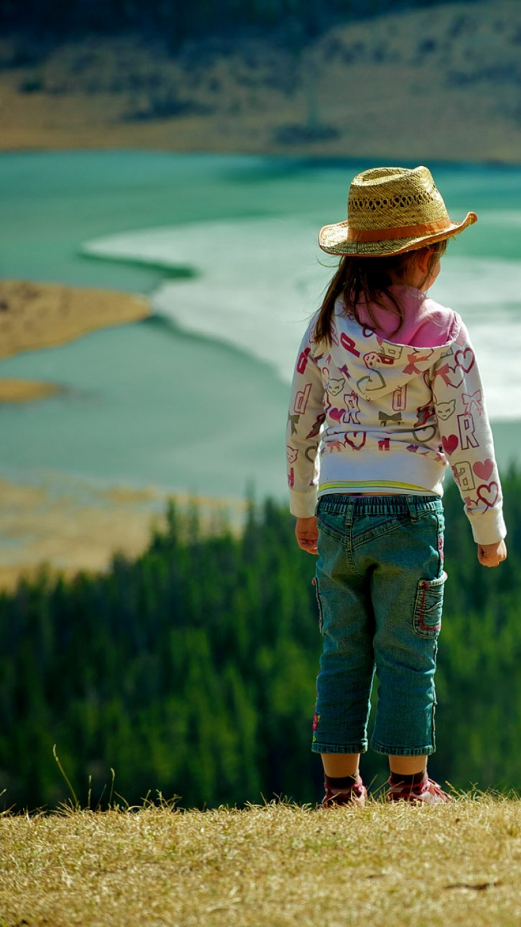 Chica en Camisa Blanca de Manga Larga y Jeans de Mezclilla Azul de Pie Sobre el Campo de Hierba Verde Durante. Wallpaper in 750x1334 Resolution