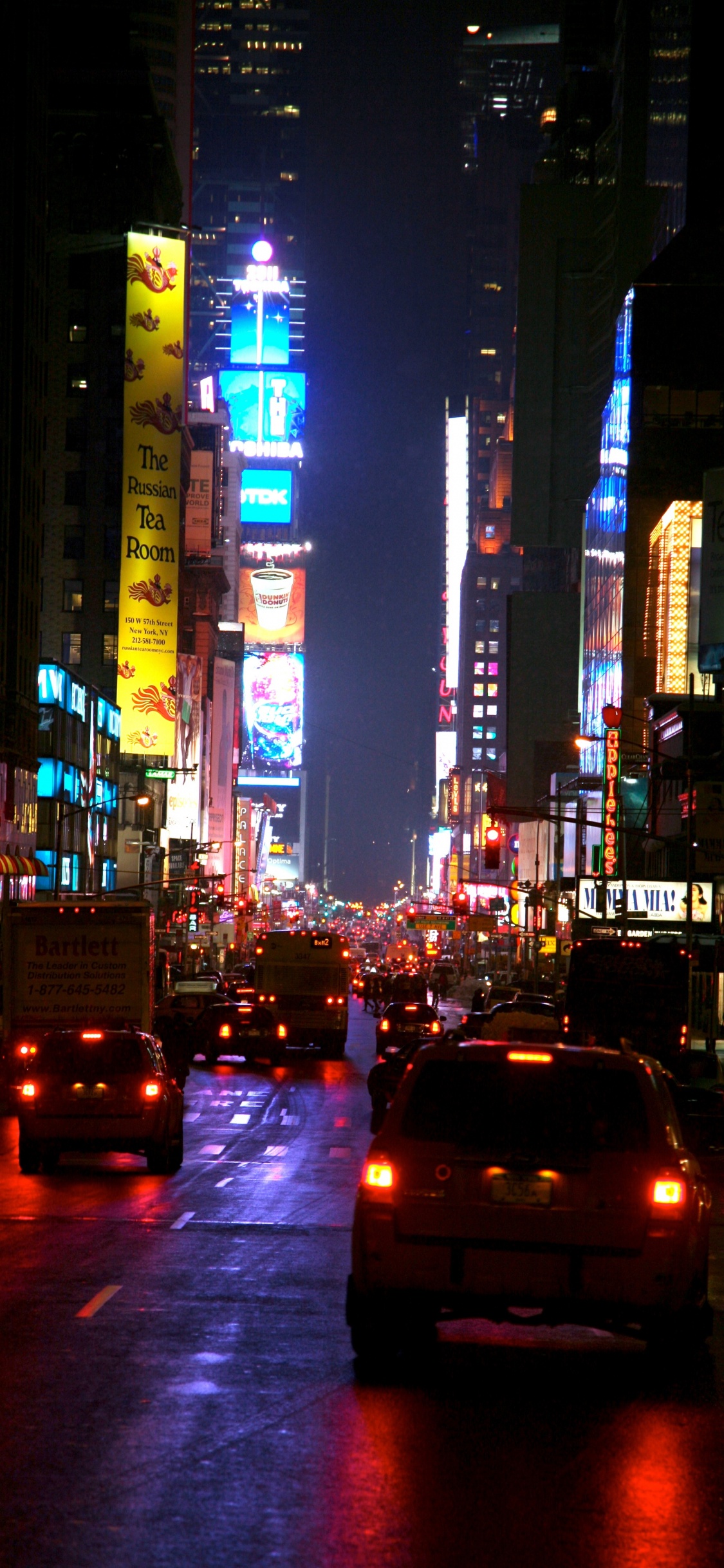 Cars on Road Between High Rise Buildings During Nighttime. Wallpaper in 1125x2436 Resolution