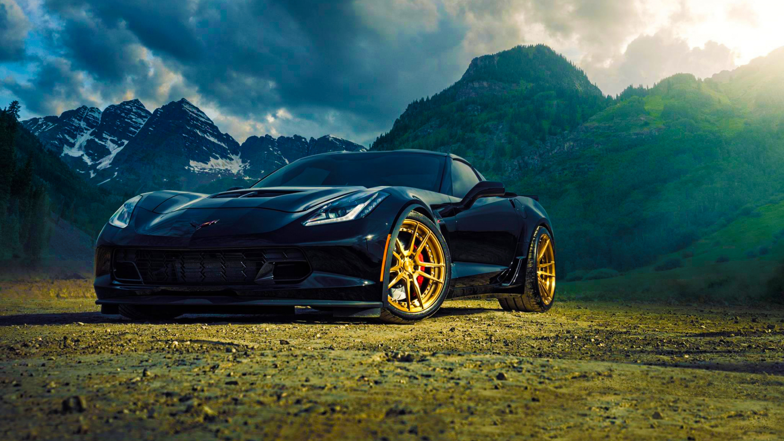 Black Porsche 911 on Brown Dirt Road Near Green Mountains Under White Clouds and Blue Sky. Wallpaper in 2560x1440 Resolution