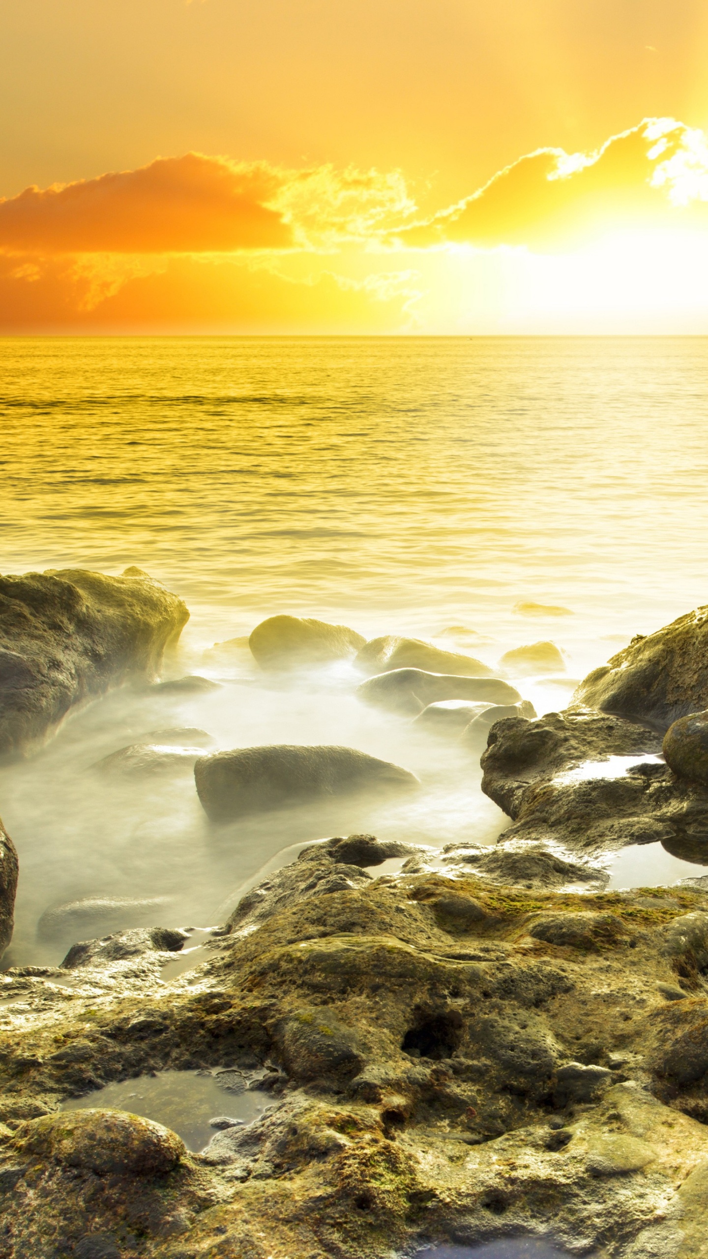 Graue Felsen Auf Gewässer Während Des Sonnenuntergangs. Wallpaper in 1440x2560 Resolution