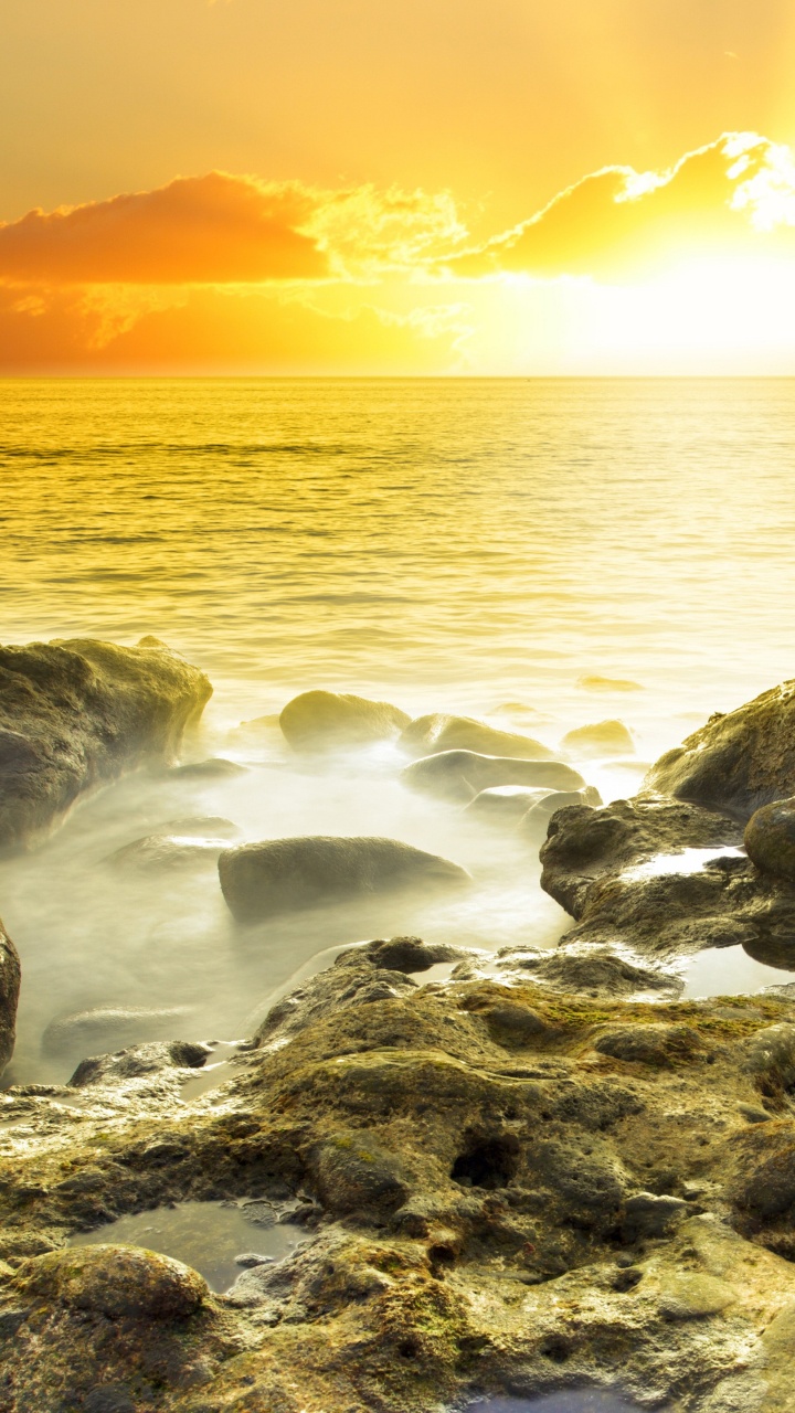 Graue Felsen Auf Gewässer Während Des Sonnenuntergangs. Wallpaper in 720x1280 Resolution