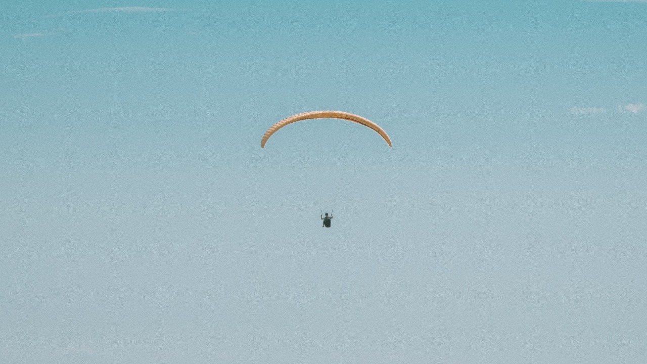 Persona en Paracaídas Bajo un Cielo Azul Durante el Día.. Wallpaper in 1280x720 Resolution