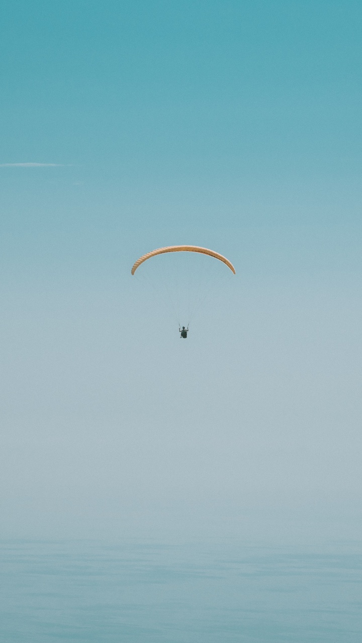 Persona en Paracaídas Bajo un Cielo Azul Durante el Día.. Wallpaper in 720x1280 Resolution
