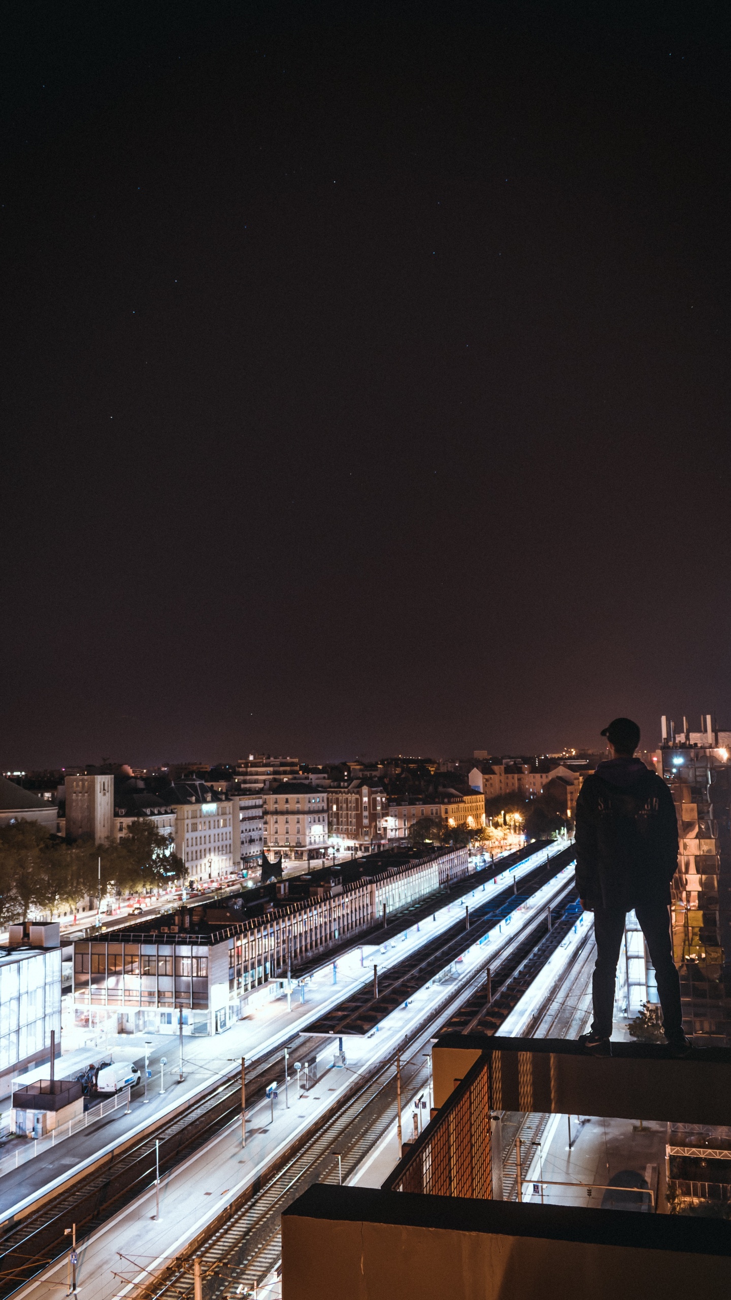Homme en Veste Noire Debout Sur un Pont en Bois Marron Pendant la Nuit. Wallpaper in 1440x2560 Resolution