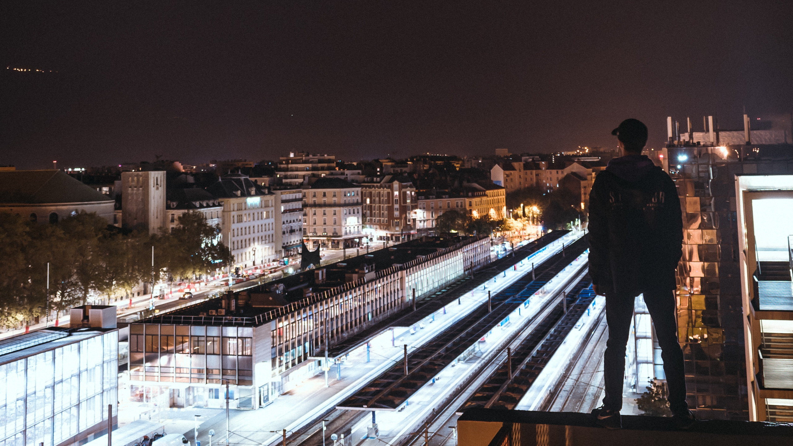 Homme en Veste Noire Debout Sur un Pont en Bois Marron Pendant la Nuit. Wallpaper in 2560x1440 Resolution