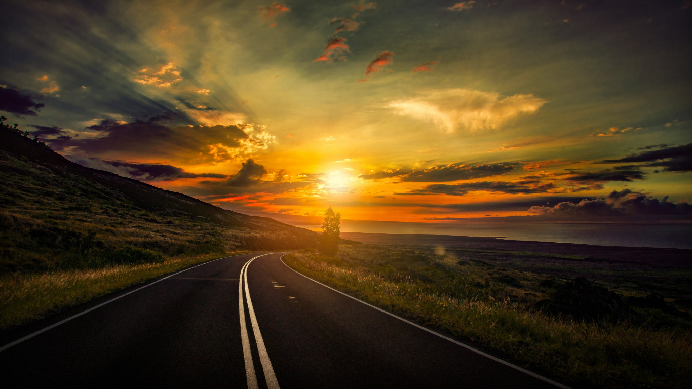 Graue Asphaltstraße Zwischen Grünem Grasfeld Während Des Sonnenuntergangs. Wallpaper in 1366x768 Resolution