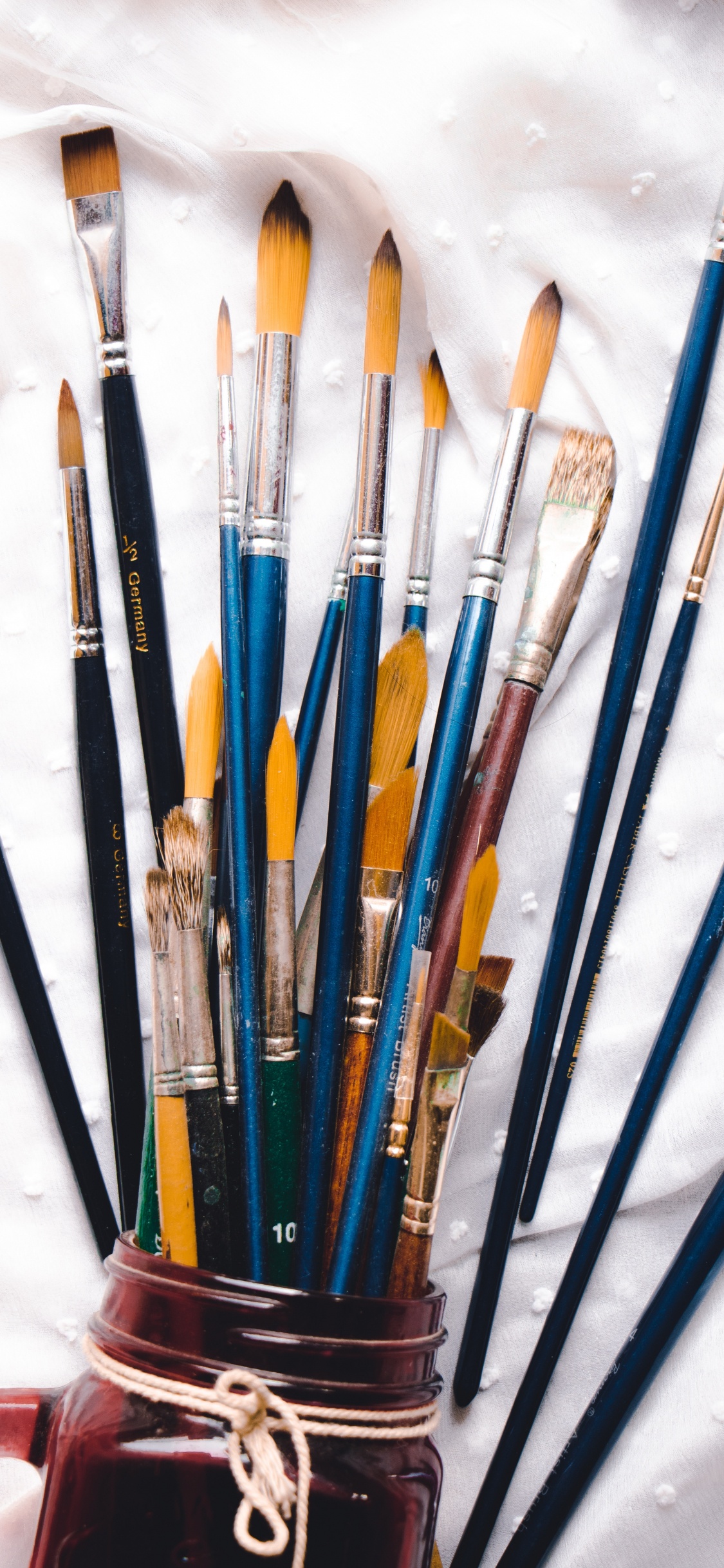 Assorted Color Paint Brushes on White Textile. Wallpaper in 1125x2436 Resolution