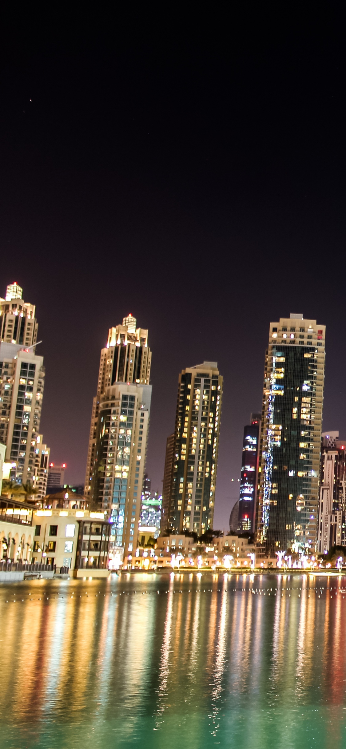 City Skyline Across Body of Water During Night Time. Wallpaper in 1125x2436 Resolution