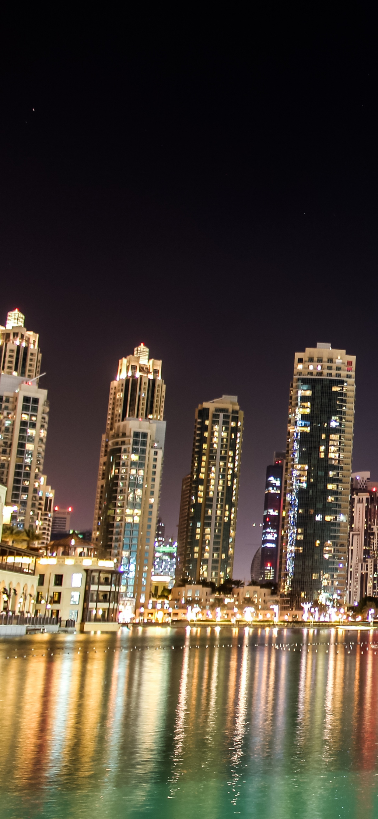 City Skyline Across Body of Water During Night Time. Wallpaper in 1242x2688 Resolution
