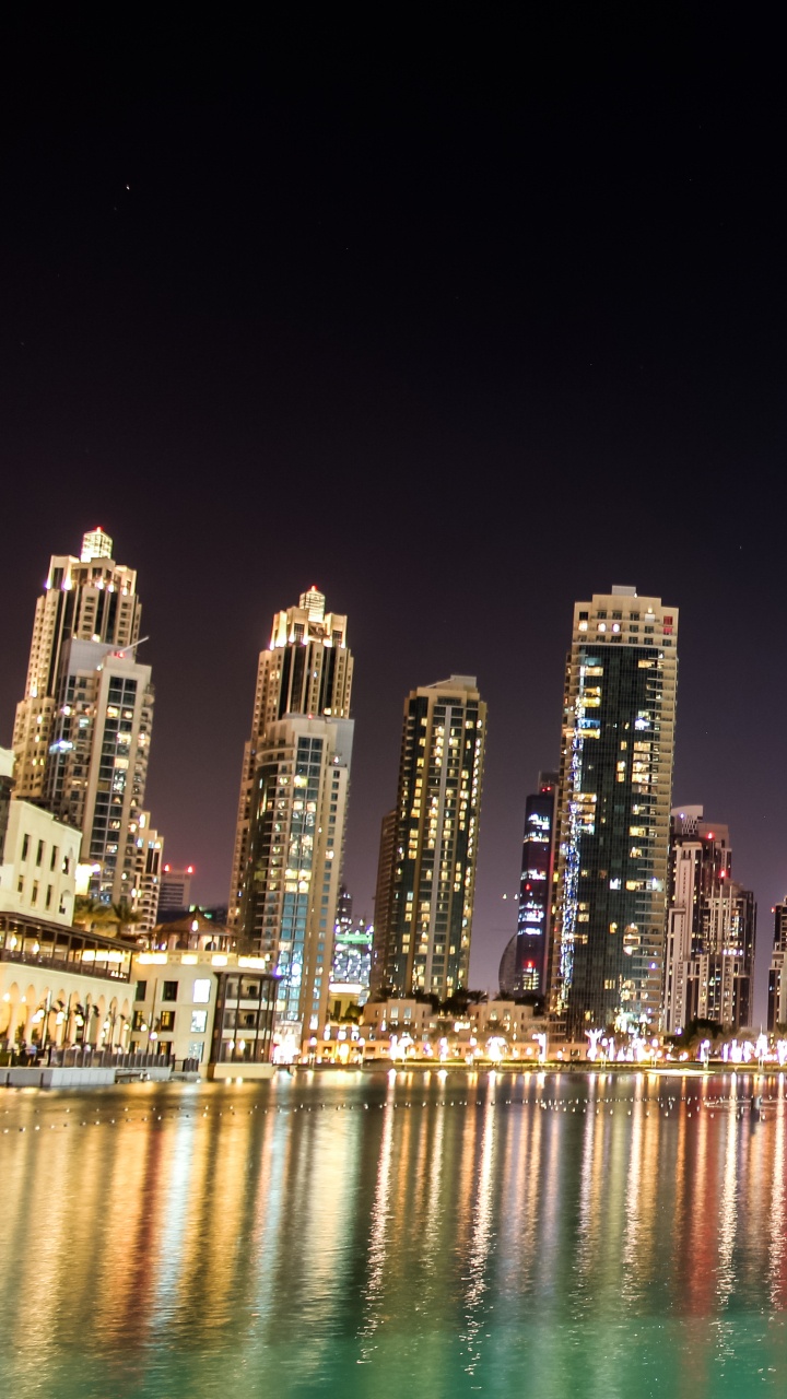 City Skyline Across Body of Water During Night Time. Wallpaper in 720x1280 Resolution