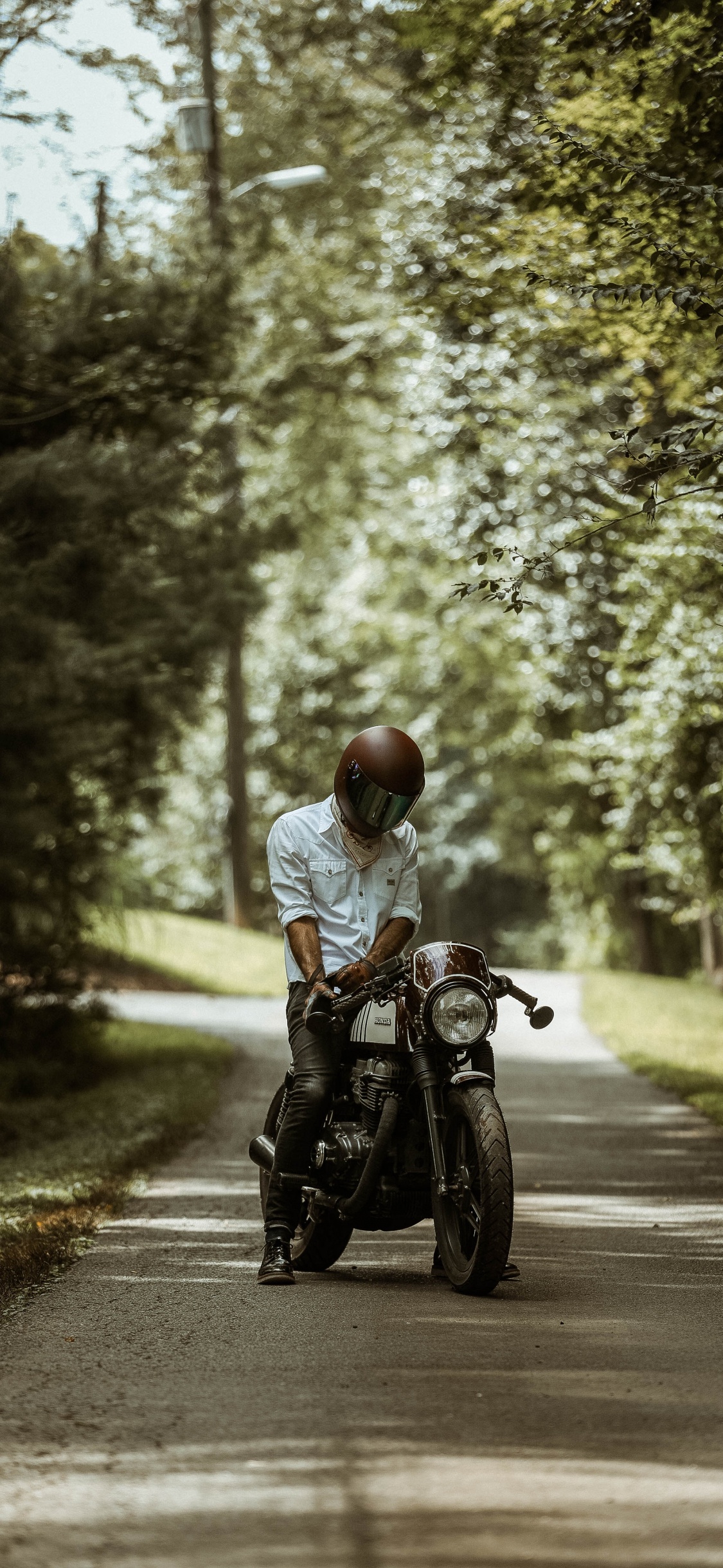 L'homme en Chemise Blanche Équitation Moto Sur Route Pendant la Journée. Wallpaper in 1125x2436 Resolution