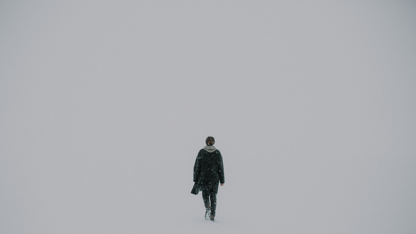 Man in Black Jacket Standing on Snow Covered Ground. Wallpaper in 1366x768 Resolution