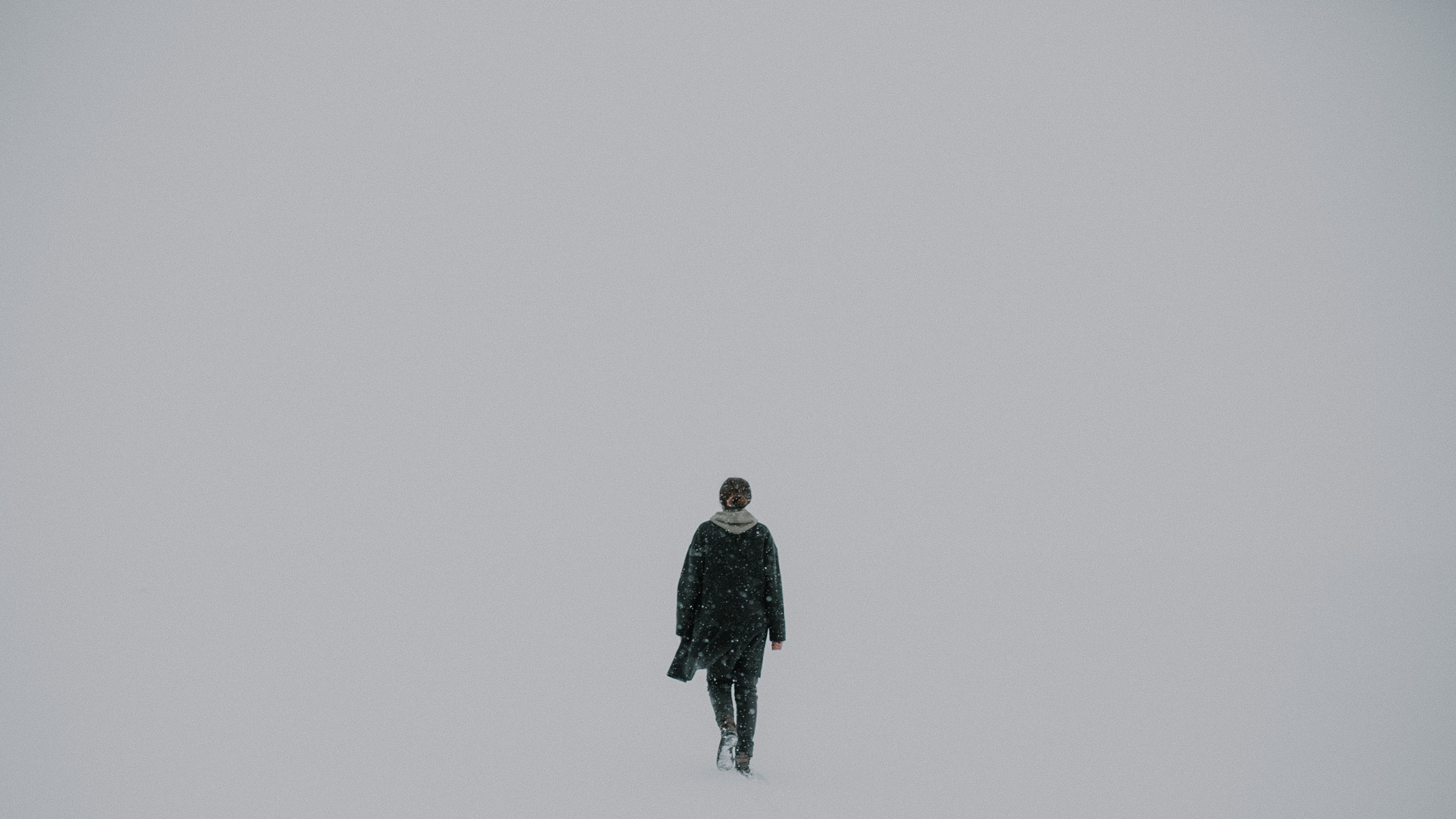 Man in Black Jacket Standing on Snow Covered Ground. Wallpaper in 2560x1440 Resolution