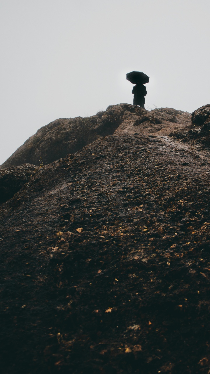 Silhouette D'homme Debout Sur Une Formation Rocheuse Pendant la Journée. Wallpaper in 720x1280 Resolution