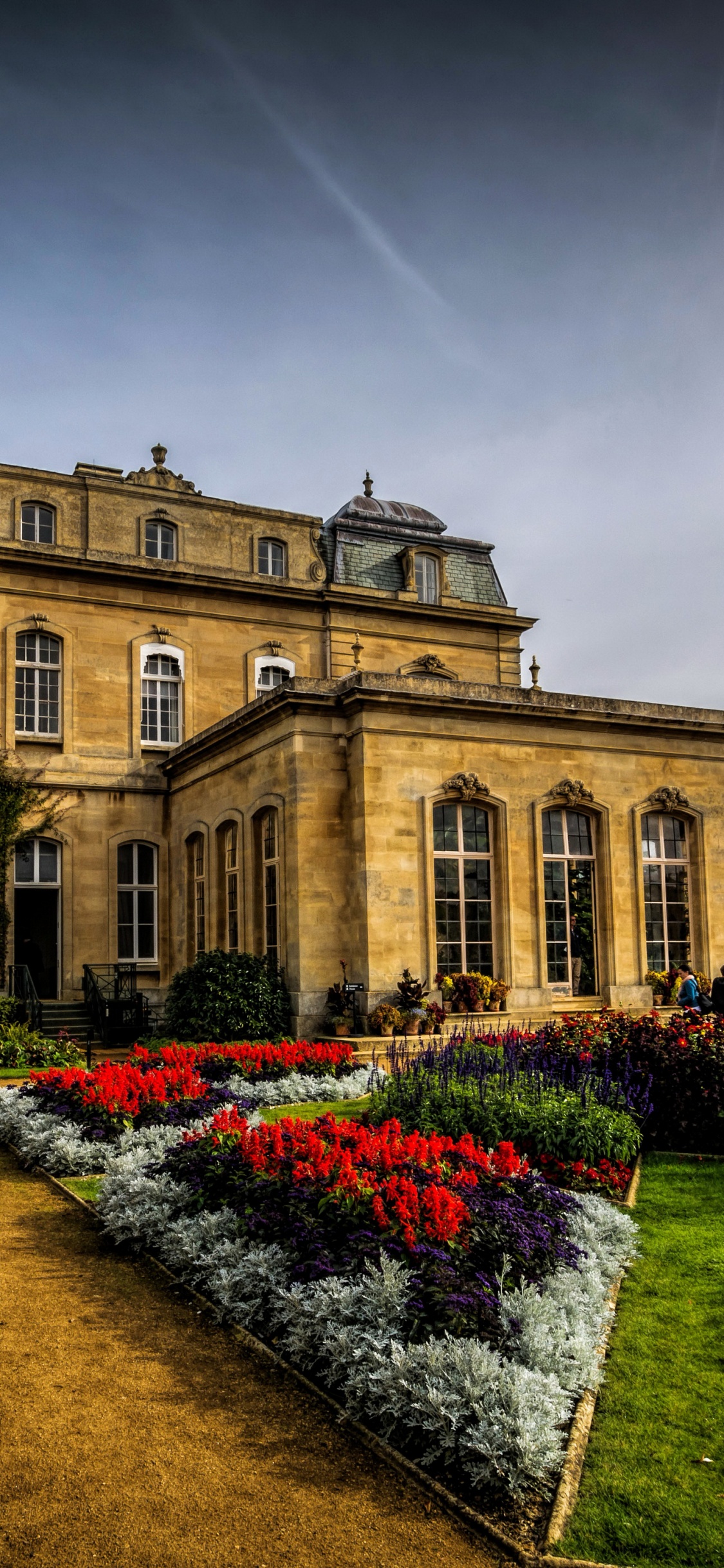 Braunes Betongebäude Mit Garten Unter Grauem Himmel. Wallpaper in 1125x2436 Resolution