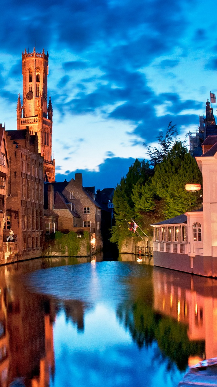 Brown Concrete Building Near River Under Blue Sky During Daytime. Wallpaper in 750x1334 Resolution