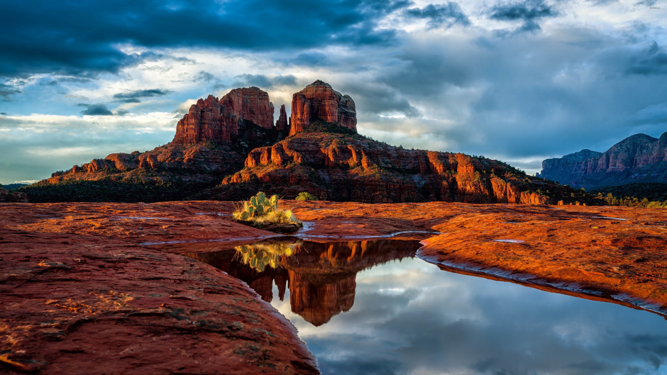 Brown Rock Formation Beside Body of Water Under Cloudy Sky During Daytime. Wallpaper in 1366x768 Resolution