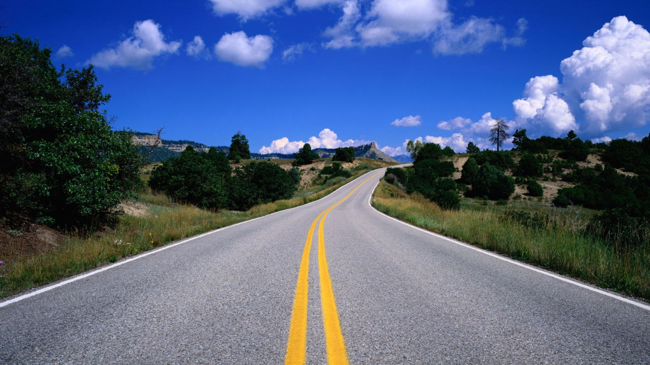Gray Concrete Road Between Green Grass Field Under Blue Sky and White Clouds During Daytime. Wallpaper in 1280x720 Resolution