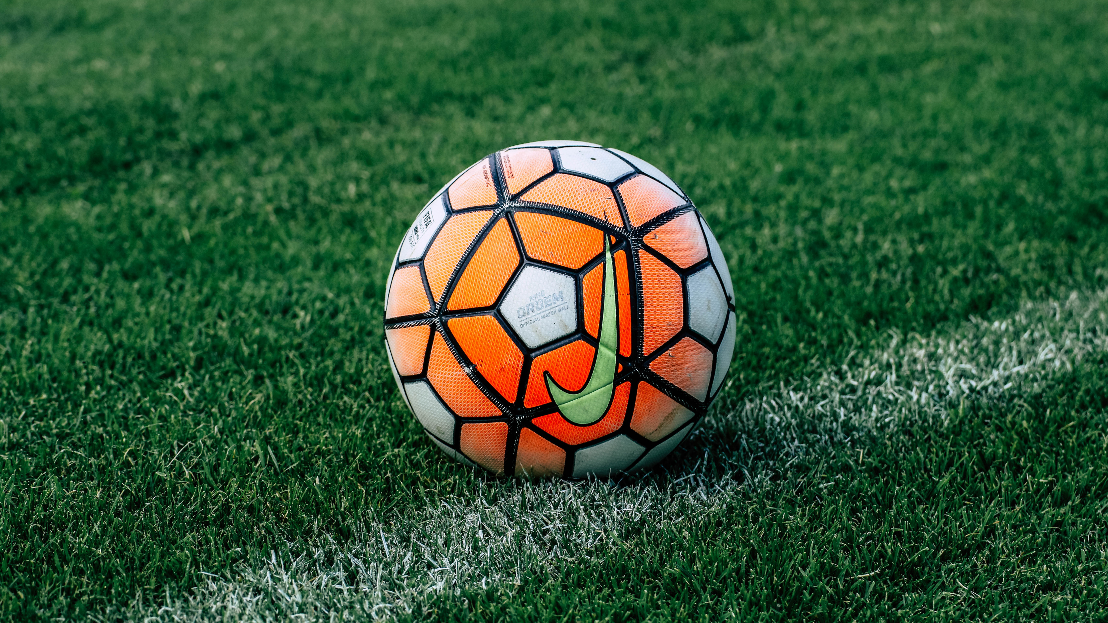 Orange and Black Soccer Ball on Green Grass Field During Daytime. Wallpaper in 3840x2160 Resolution