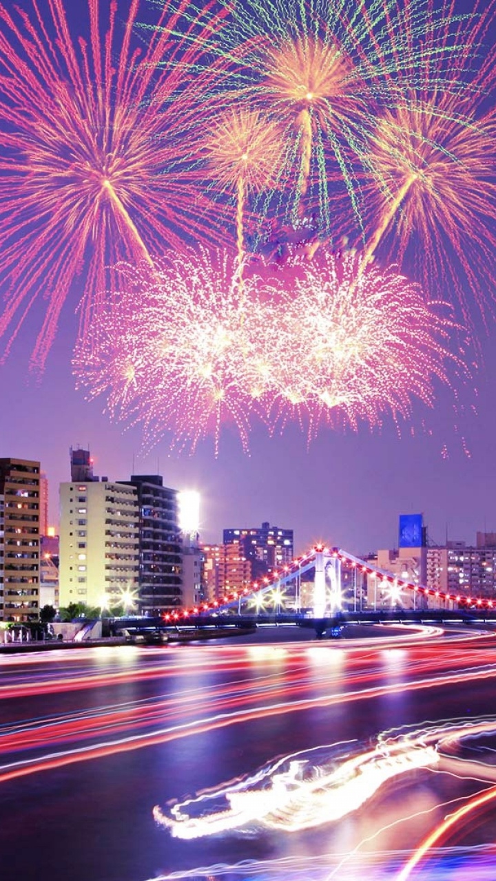 Feuerwerk Über Stadtgebäuden Während Der Nacht. Wallpaper in 720x1280 Resolution