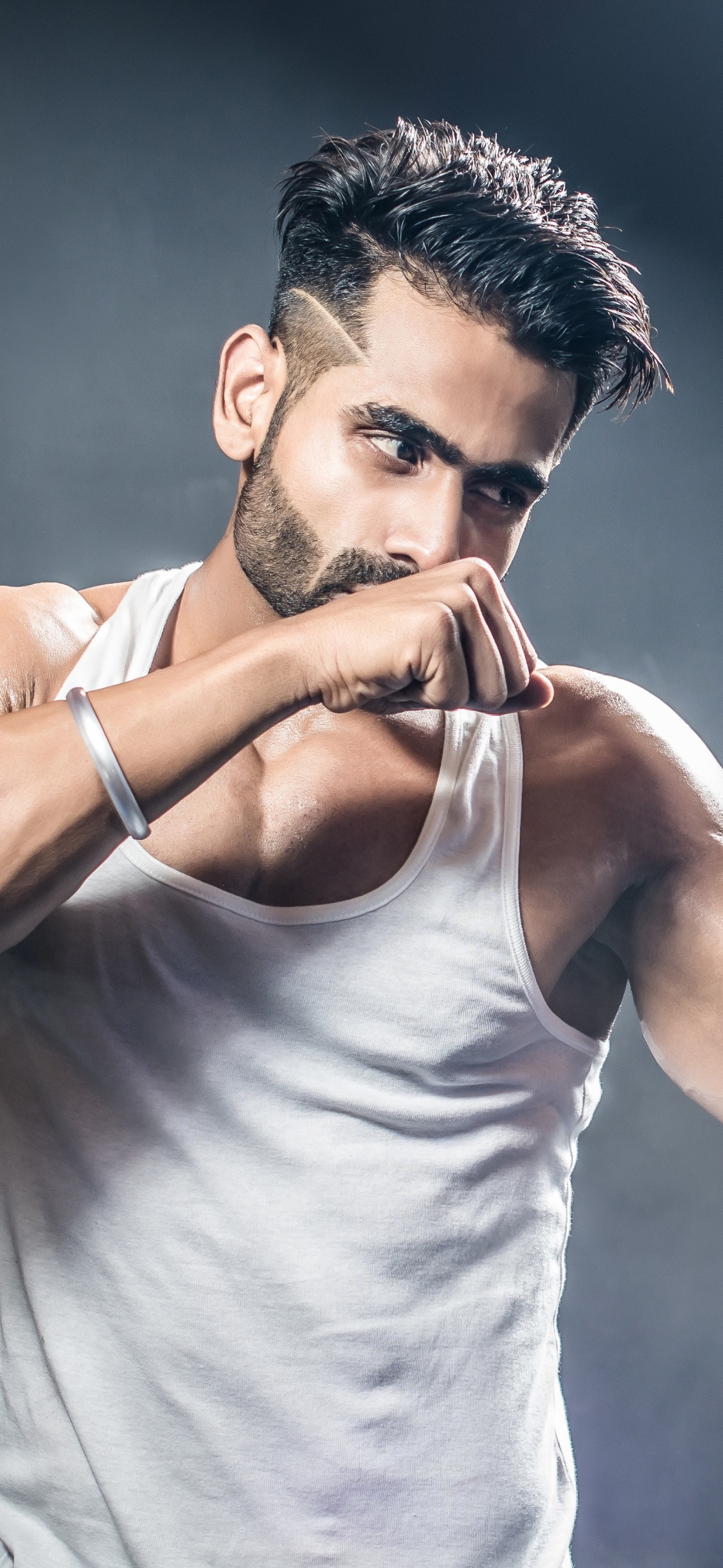 Man in White Tank Top Holding Blue and White Nike Boxing Gloves. Wallpaper in 1125x2436 Resolution