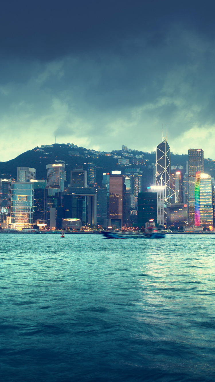 Horizonte de la Ciudad a Través Del Cuerpo de Agua Durante la Noche.. Wallpaper in 750x1334 Resolution