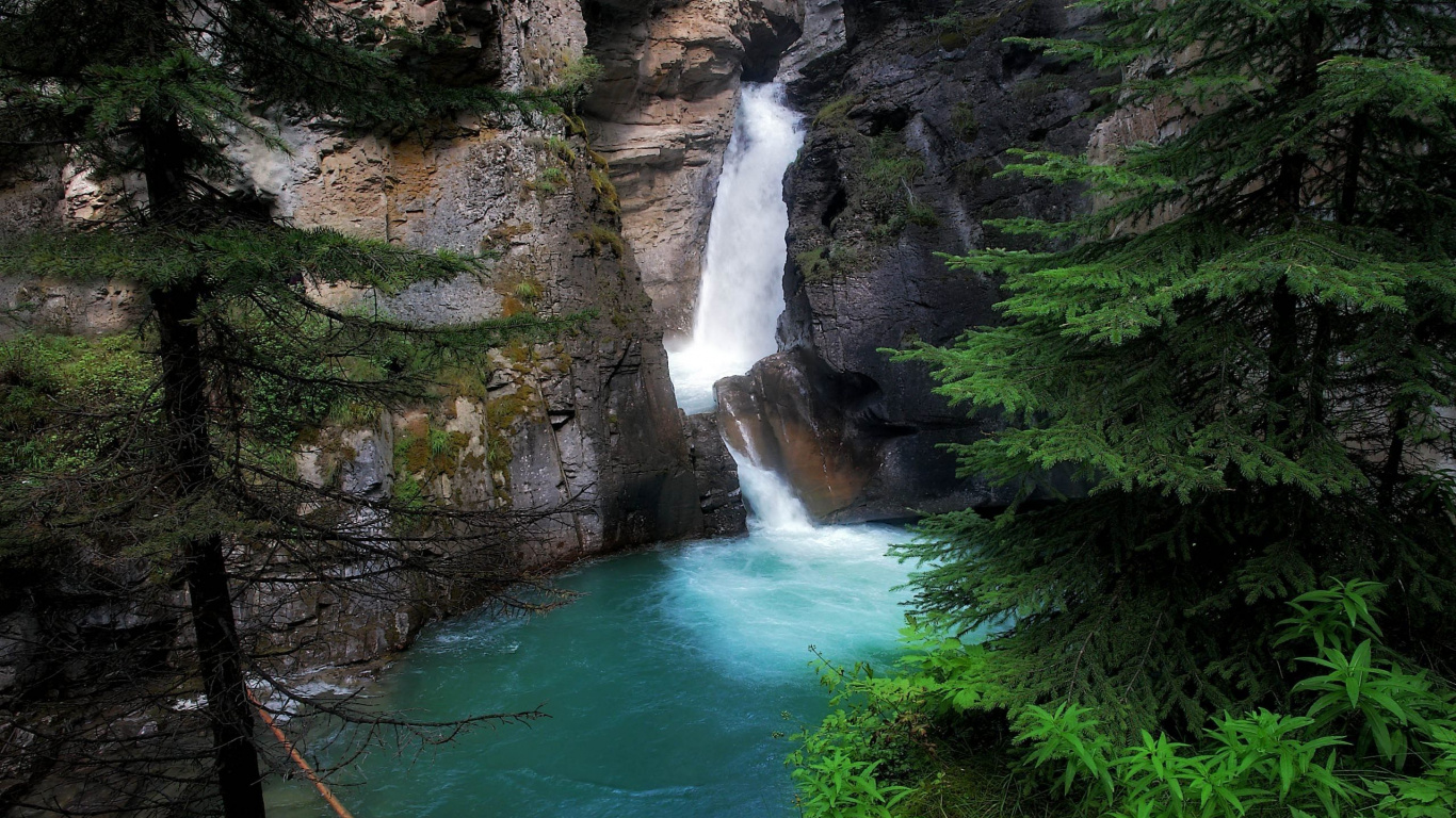 Waterfalls Between Brown Rocky Mountain During Daytime. Wallpaper in 1366x768 Resolution